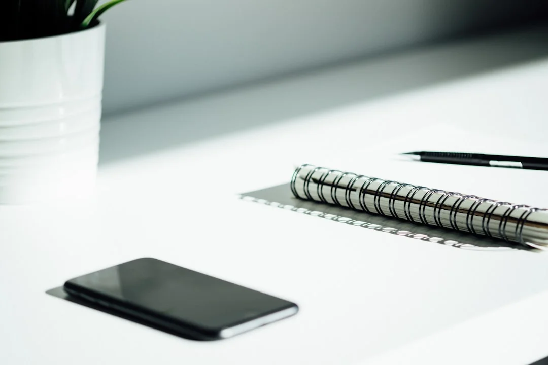 Des mains utilisant une tablette à côté d’un ordinateur portable dans un bureau à domicile, illustrant la navigation en ligne.